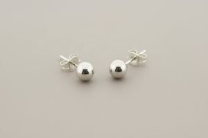 Pair of silver ball earrings on a gray background