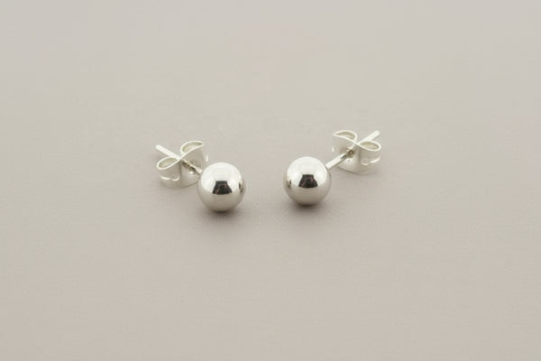 Pair of silver ball earrings on a gray background