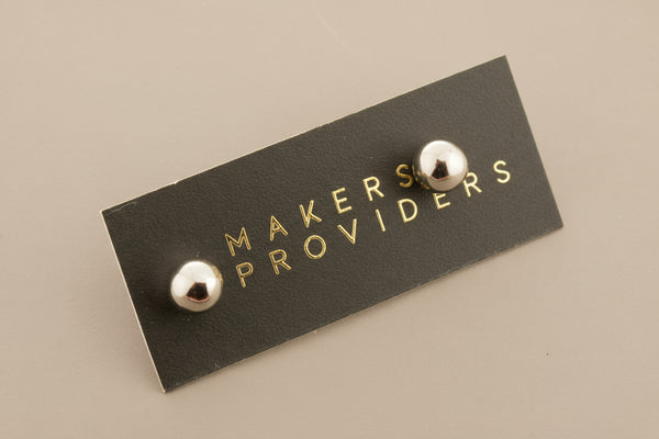 Black rectangular label with 'MAKERS PROVIDERS' text and two silver knobs on a gray background