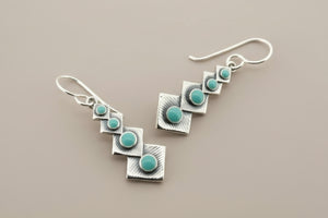 Silver earrings with turquoise stones on a gray background