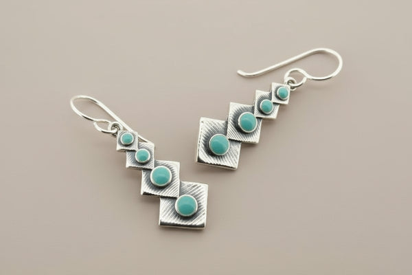 Silver earrings with turquoise stones on a gray background