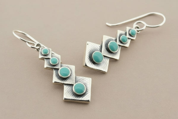 Silver earrings with turquoise stones on a gray background