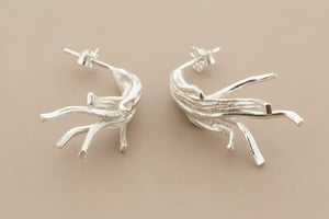 Silver branch-like earrings on a dark gray background