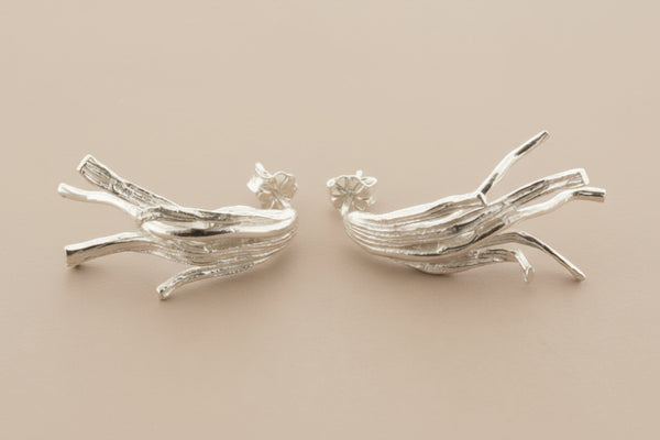 Pair of silver branch-like earrings on a gray background