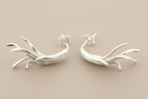 Pair of silver branch-like earrings on a gray background