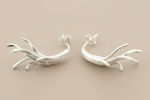 Pair of silver branch-like earrings on a gray background