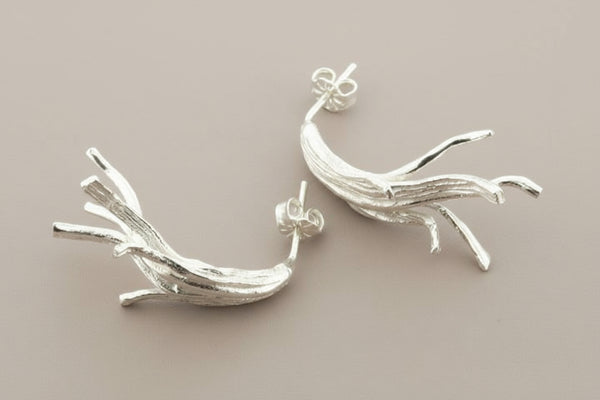 Silver branch-like earrings on a dark gray background