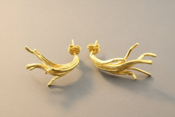Pair of gold branch-shaped earrings on a gray background