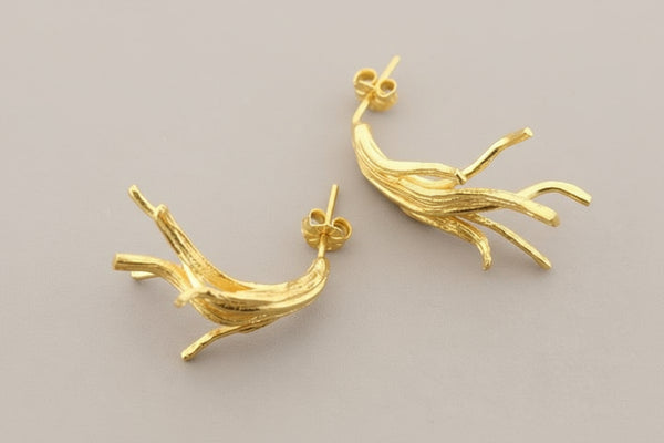 Pair of gold branch-shaped earrings on a gray background