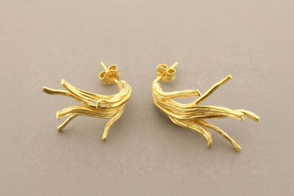 Gold branch-shaped earrings on a gray background