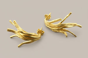 Pair of gold branch-like earrings on a gray background