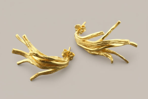 Pair of gold branch-like earrings on a gray background