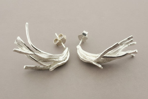 Pair of silver branch-like earrings on a dark gray background