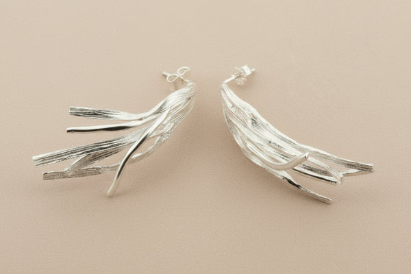 Silver leaf-shaped earrings on a dark gray background