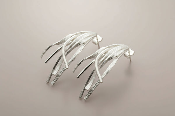 Pair of silver leaf-like earrings on a dark gray background