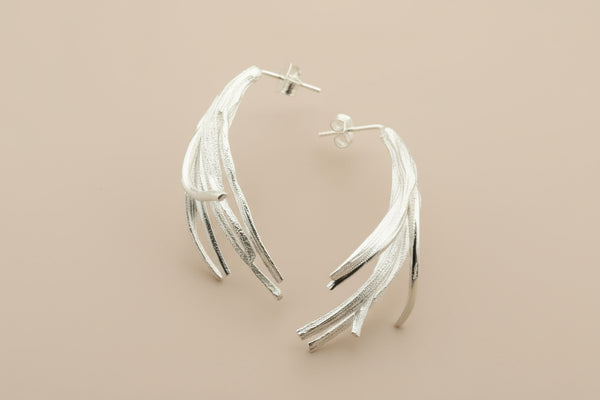 Silver leaf-shaped earrings on a gray background