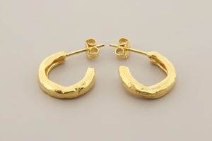 Gold hoop earrings on a gray background