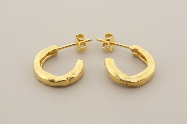 Gold hoop earrings on a gray background