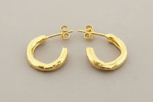 Gold hoop earrings on a gray background