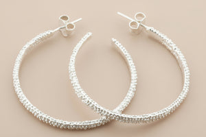 Silver hoop earrings on a gray background