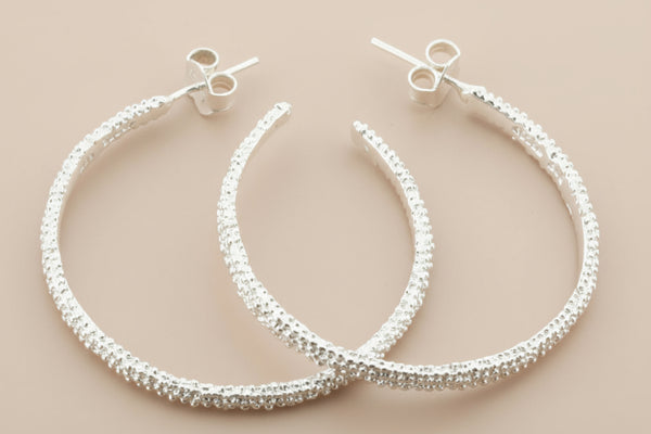 Silver hoop earrings on a gray background
