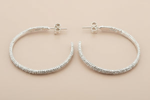 Pair of silver hoop earrings on a gray background