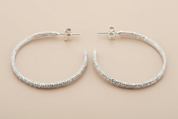 Pair of silver hoop earrings on a gray background
