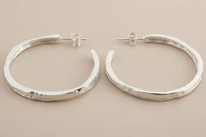 Pair of silver hoop earrings on a gray background