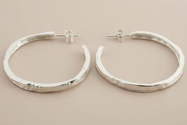 Pair of silver hoop earrings on a gray background