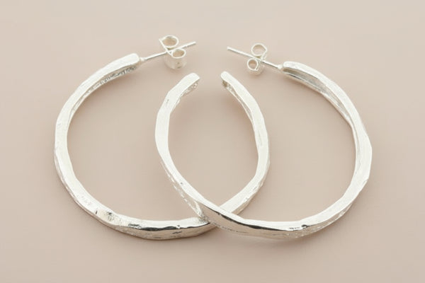 Pair of silver hoop earrings on a dark gray background