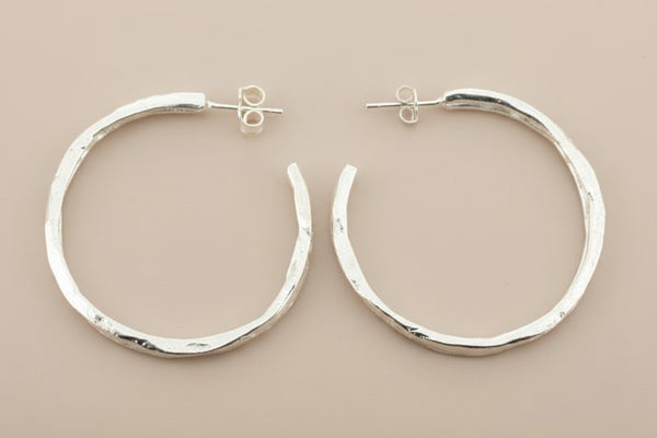 Pair of silver hoop earrings on a gray background