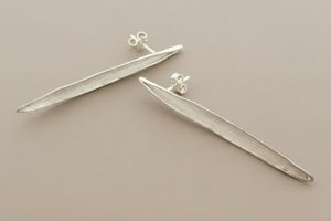Pair of silver leaf-shaped earrings on a gray background