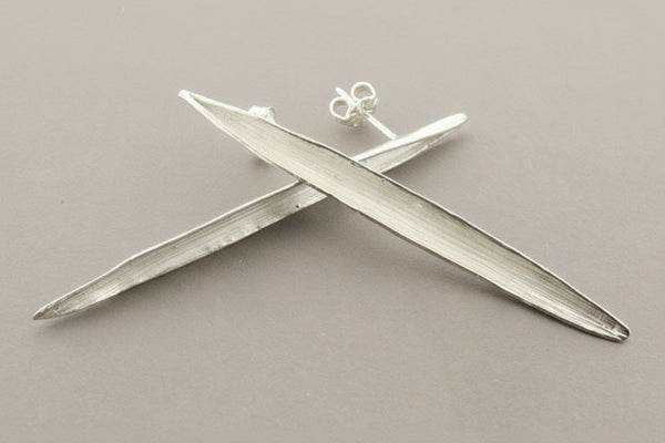 Silver airplane-shaped earrings on a gray background