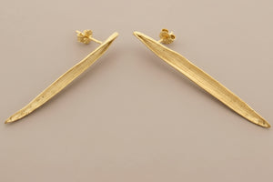 Gold earrings on a gray background