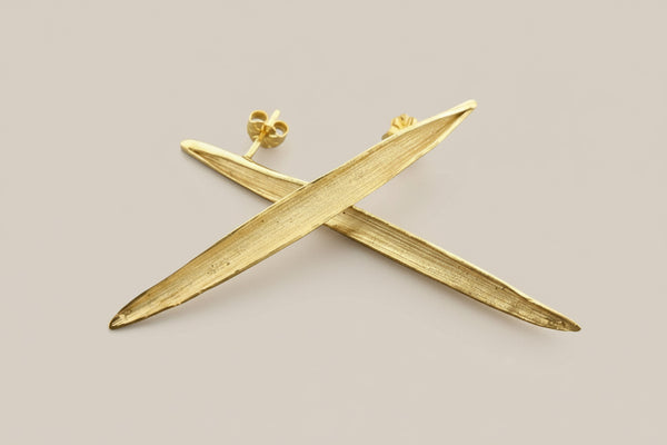 Gold earrings on a gray background