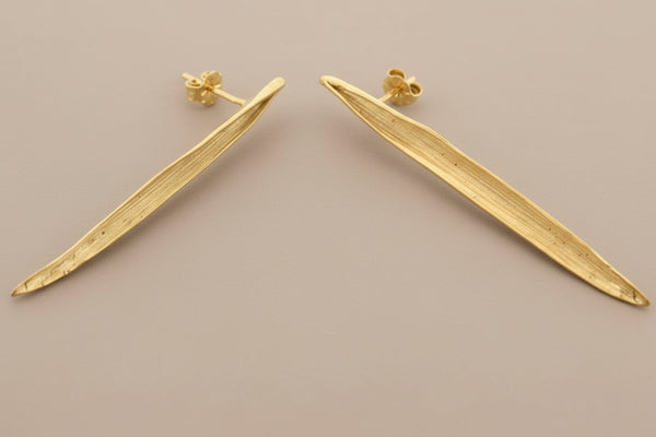 Gold earrings on a gray background