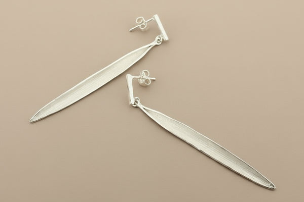 Pair of silver leaf-shaped earrings on a gray background