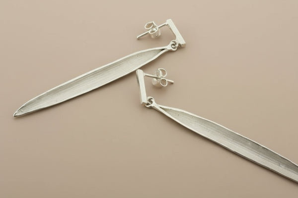 Silver leaf-shaped earrings on a gray background