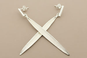 Silver X-shaped earrings on a gray background