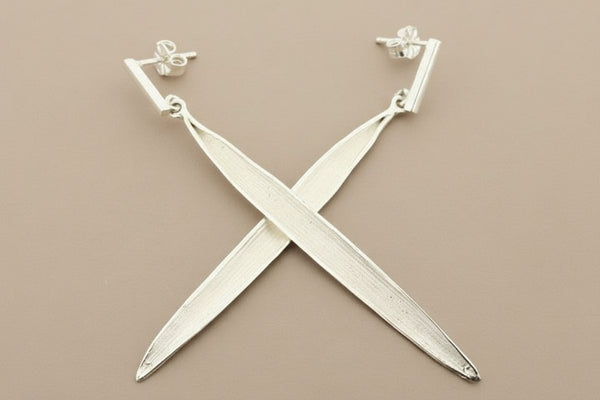 Silver X-shaped earrings on a gray background