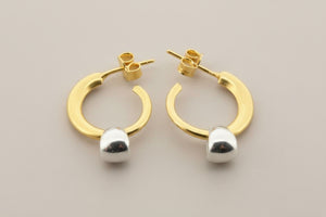 Gold hoop earrings with silver caps on a gray background