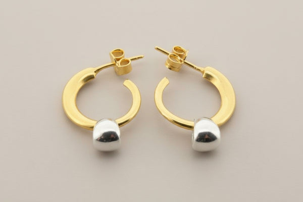 Gold hoop earrings with silver caps on a gray background