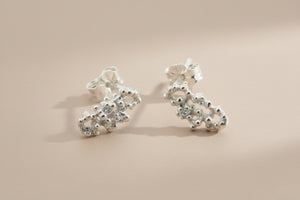 Pair of silver floral earrings on a gray background