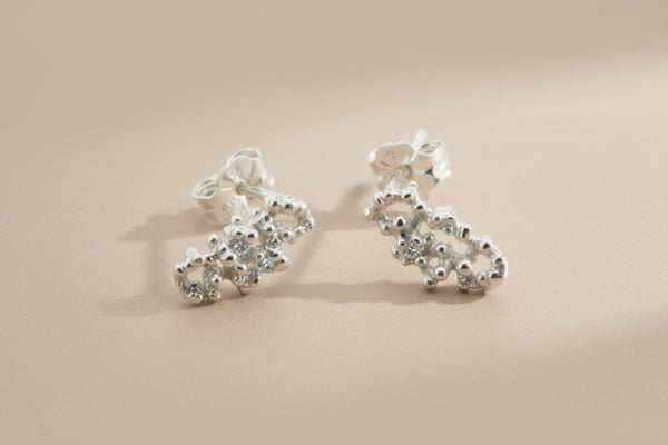 Pair of silver floral earrings on a gray background