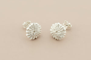 Pair of silver floral earrings on a gray background