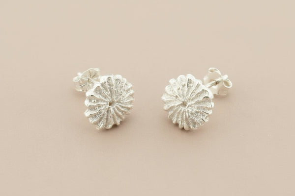 Pair of silver floral earrings on a gray background