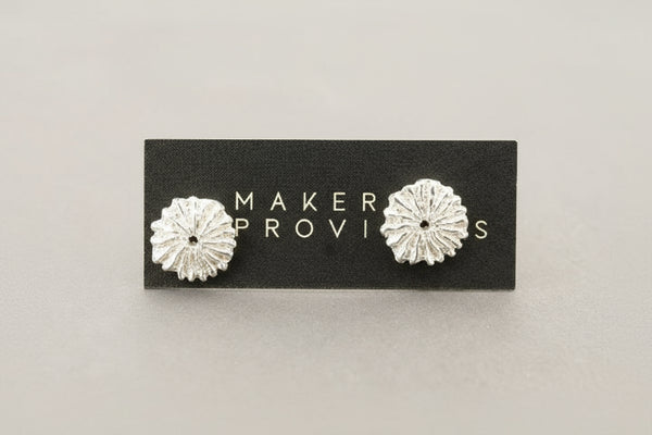 Silver floral earrings on a 'Maker Provisions' card against a gray background