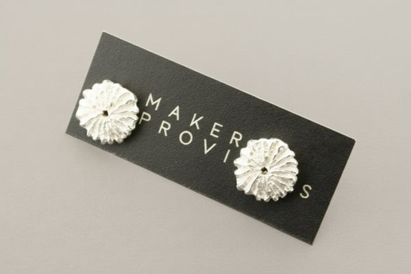 Silver floral earrings against a gray background