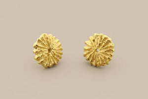 Pair of gold floral earrings on a gray background