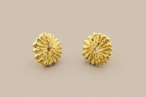 Pair of gold floral earrings on a gray background
